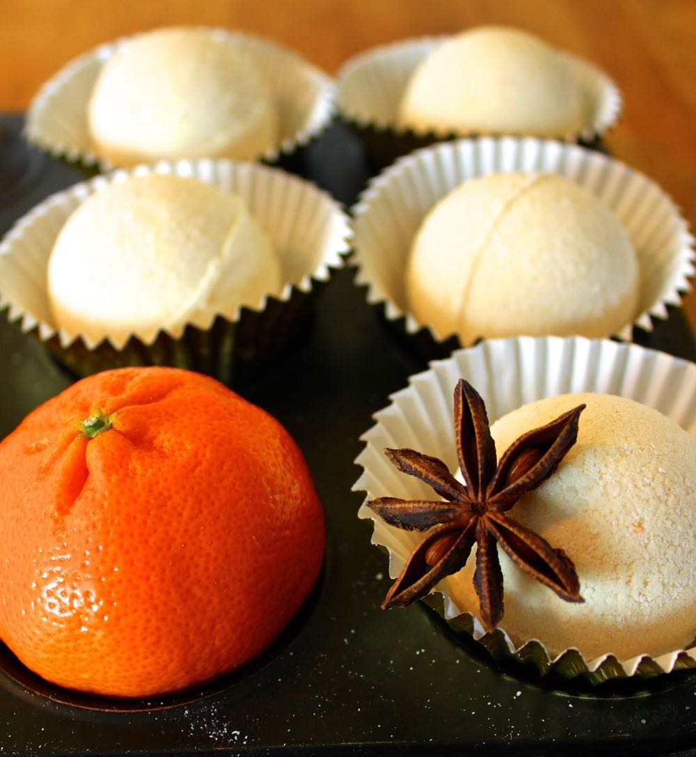 Homemade Bath Bombs in paper cups alongside a satsuma.