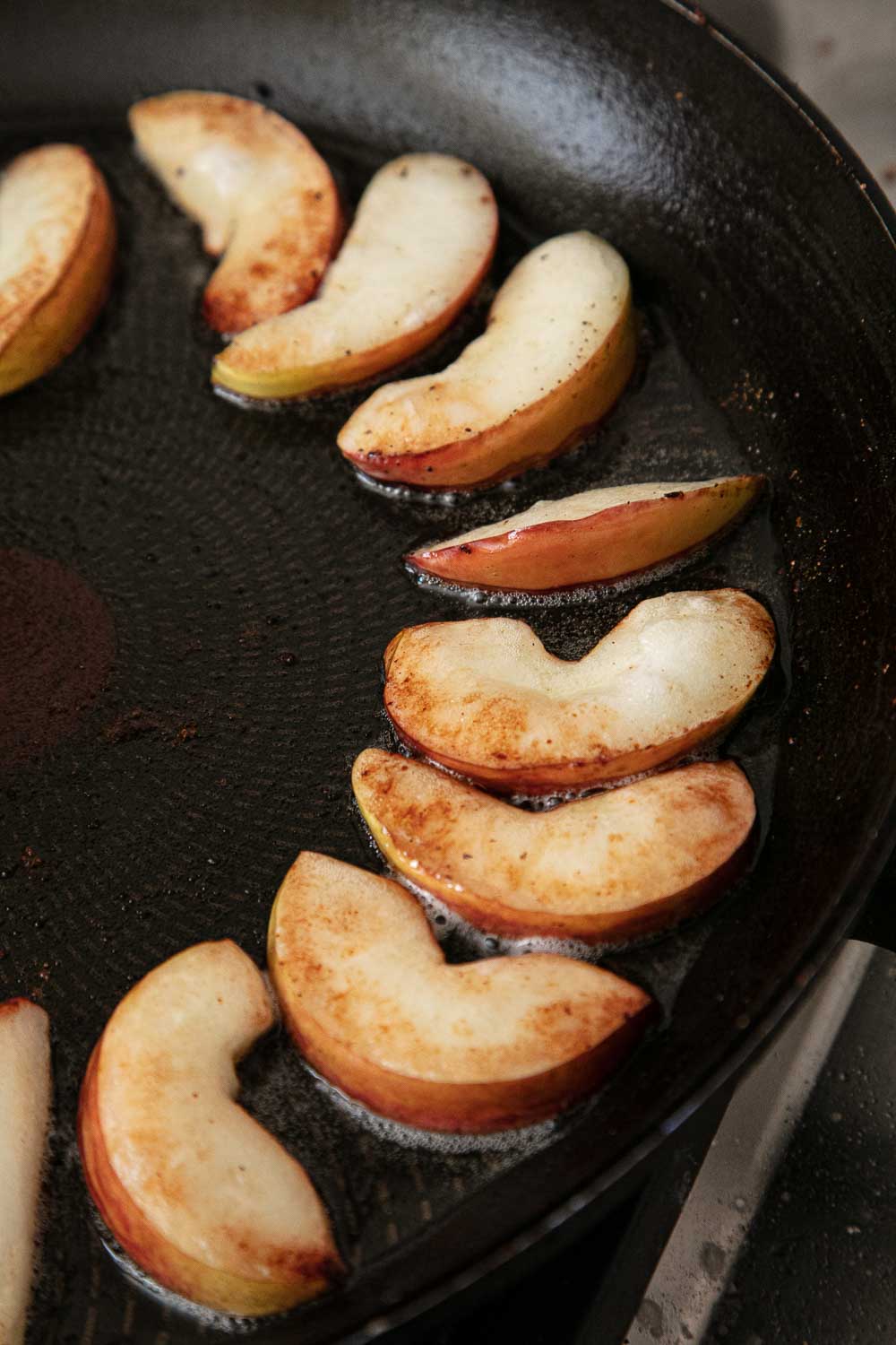 Apple slices frying in a frying pan. 