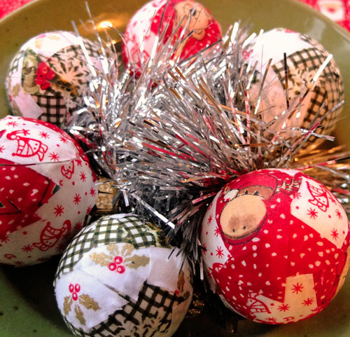 Homemade Christmas Baubles made from scraps of fabric, sitting in a bowl with silver tinsel.