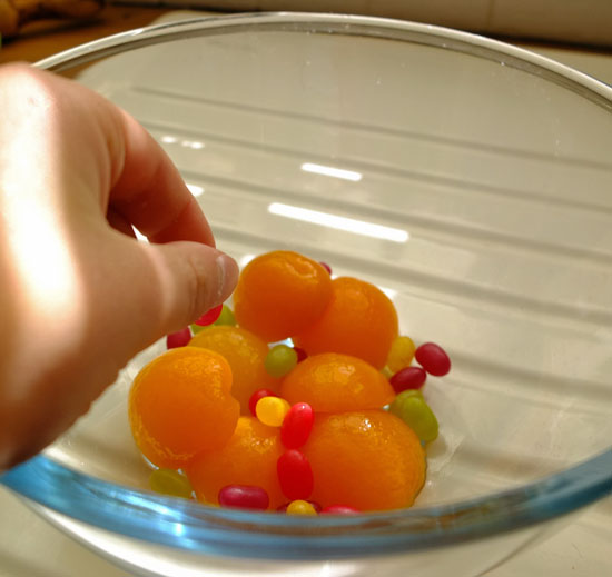 Apricots scattered with jelly beans in a glass bowl.