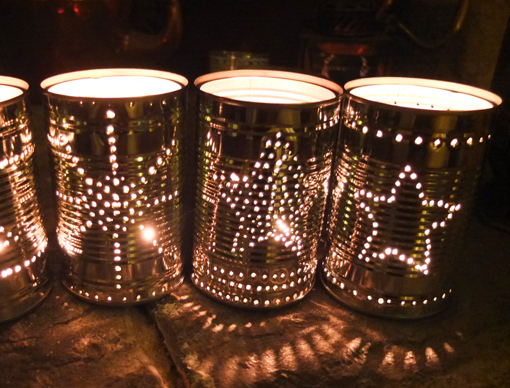 Tin cans turn into  a lantern with star designs with light in the inside
