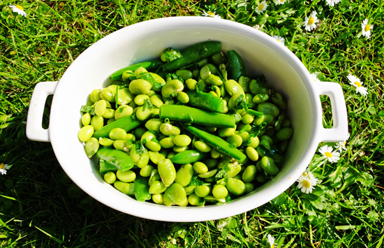 Crunchy green bean salad in a white dish, outside on the lawn.