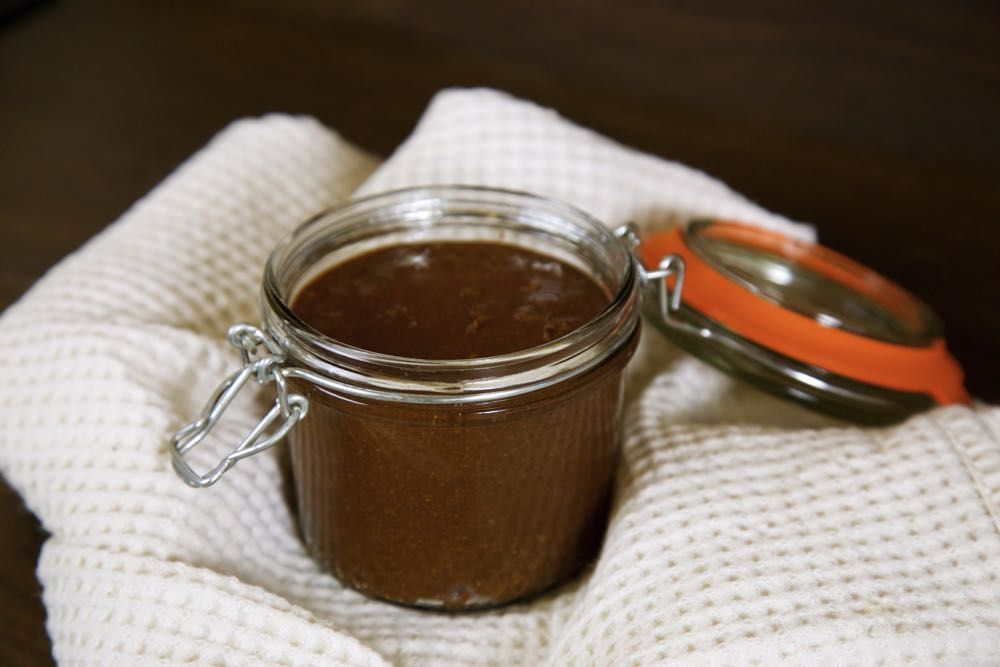 A jar of homemade vegan Nutella on a waffle tea towel. 