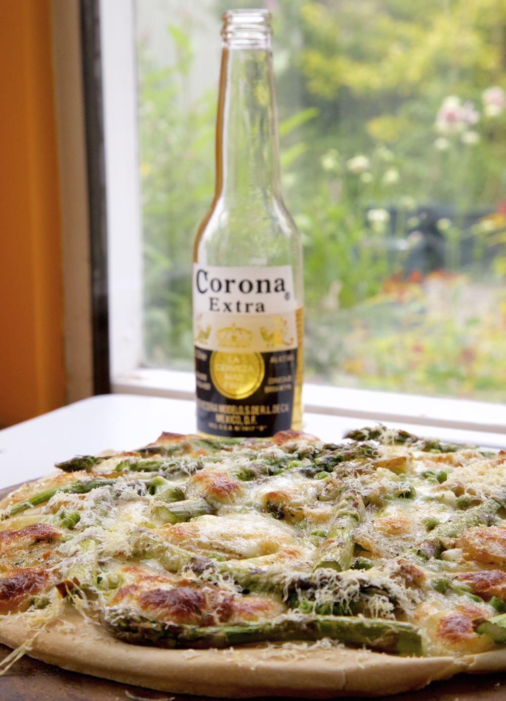Asparagus Pizza with Jersey Royal Potatoes, Spring Onions and Peas, served with beer.