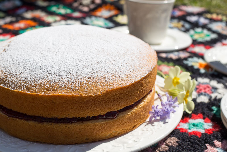 Egg Free Sponge Cake on a plate with spring flowers.
