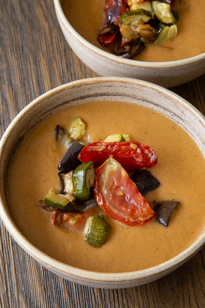 A bowl of smooth ratatouille soup topped with roasted Mediterranean vegetables.
