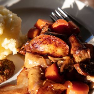 Vegan sausage, cider and apple casserole with mashed potato and grain mustard.