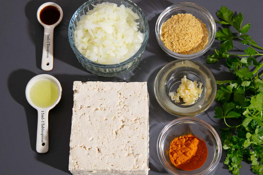 Ingredients for scrambled tofu, laid out on a chopping board.