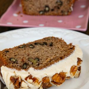 A slice of coffee and walnut cake topped with coffee buttercream and chopped walnuts.