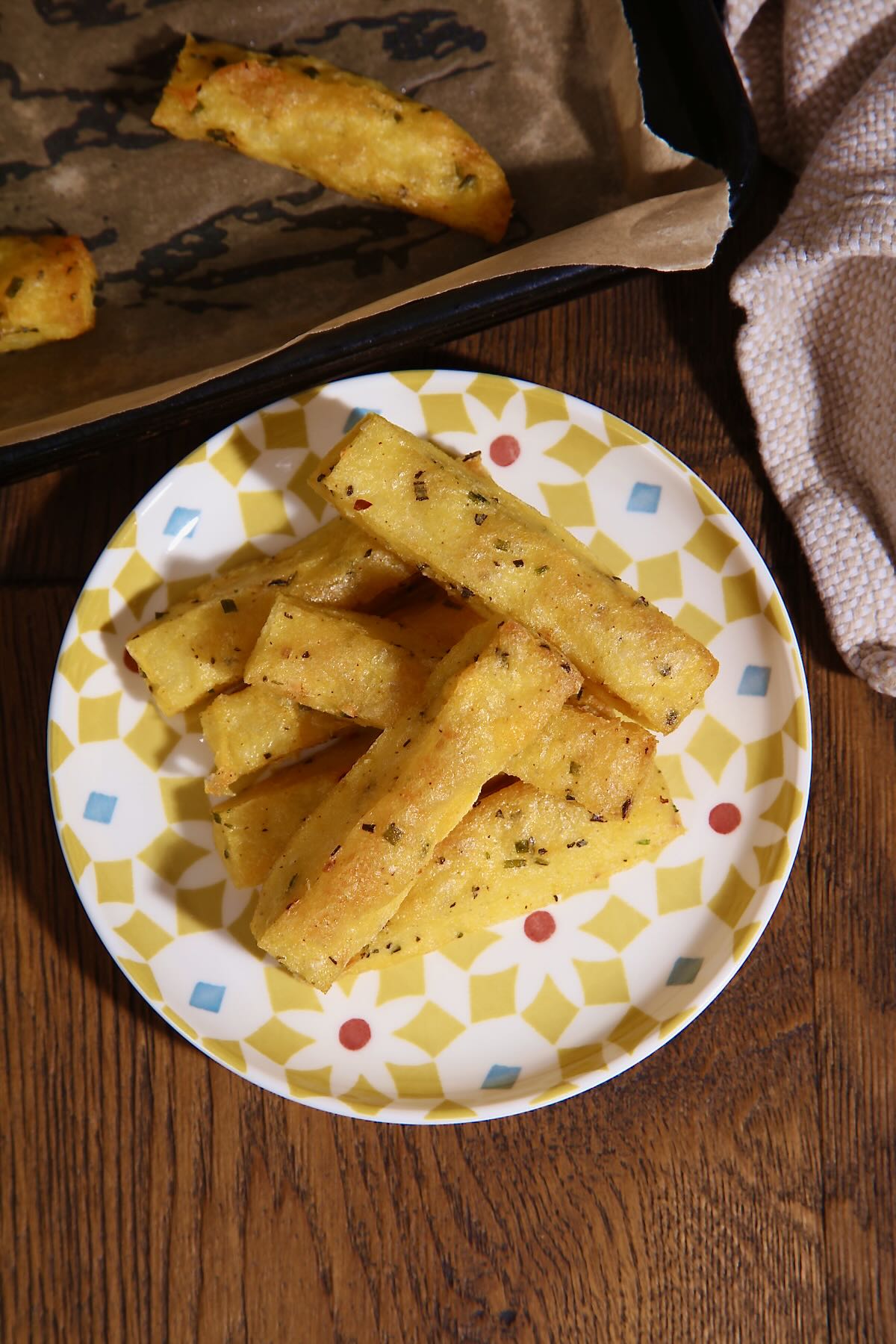Seven polenta chips are piled on a small, brightly patterned tapas plate.